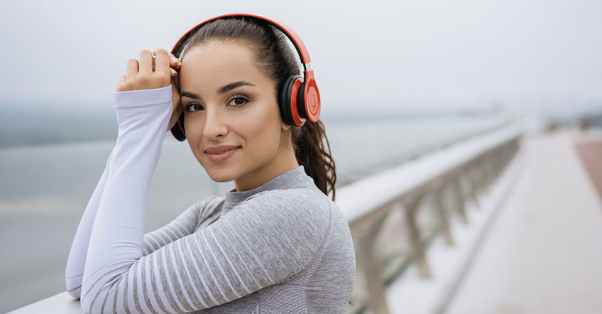 Man wearing wireless headset taking notes beside computer monitor and keyboard