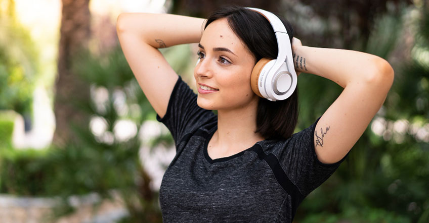 Woman using wireless headset while typing on laptop in home office