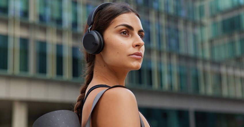 Professional using wireless headset while reviewing documents beside open laptop