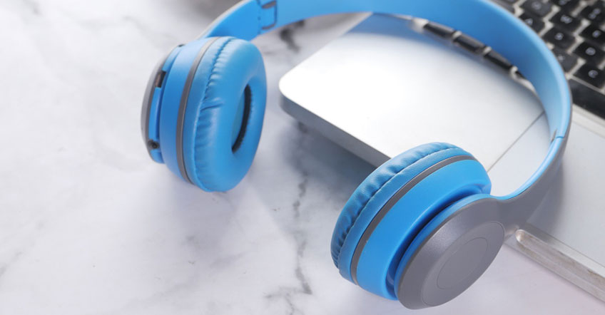 Office worker smiling while listening through wireless headset at workstation